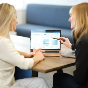 Two people looking at charts on a laptop